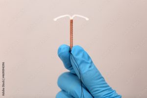 An gloved hand holding an IUD against a nude background in a blog post about 10 GUARANTEED CONTRACEPTION METHODS FOR YOU IN 2023