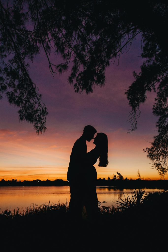An silhouette image of two lovers, in the background is the glistening surface of a river. This image is included in a blog post on how to deal with intimacy if you hate physical touch.