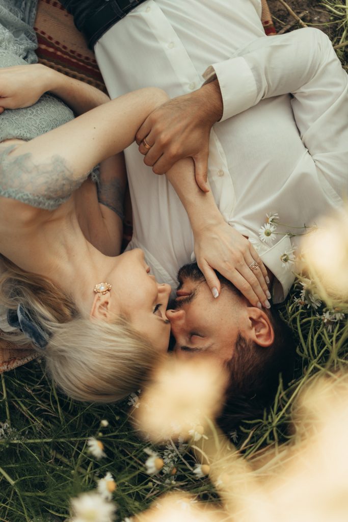 An image of a man and woman laying on the grass in a bog post on How to Open Up To Your Partner.